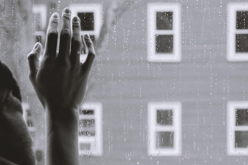 Black and White photo of a persons hand against a window while it's raining outside. Dealing with the loss of a spouse