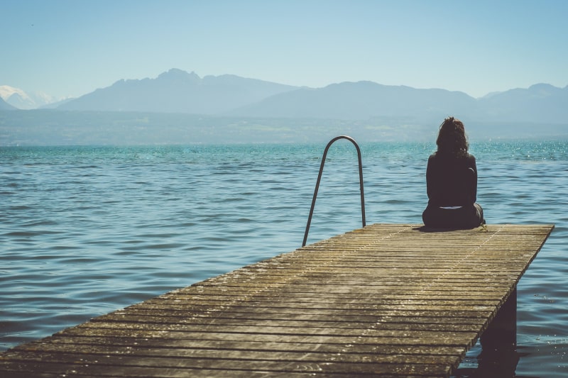 Girl sitting at the end of a dock looking into the distance. how to support the bereaved